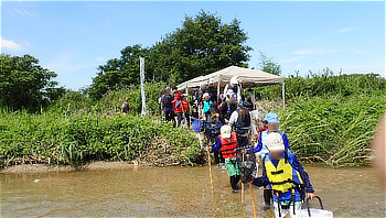 石川中流での魚とり観察会に参加し、ライフジャケットを着用して川の中を歩く親子連れ