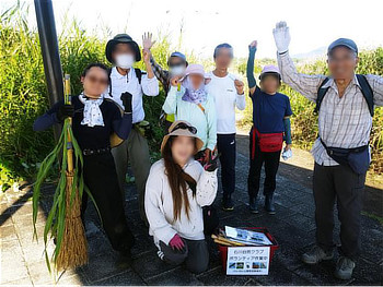 茂みの中に屈み込み、足元の草を確認しながら除草作業を行う参加者たち