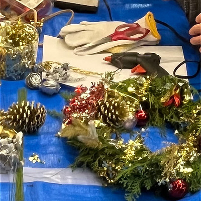 手作りのクリスマスリースと作業台に置かれたグルーガンやハサミなどの道具