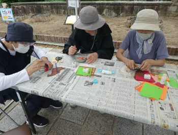 参加された女性たち。石に葉っぱ型の色々な色用紙を貼り付けます。