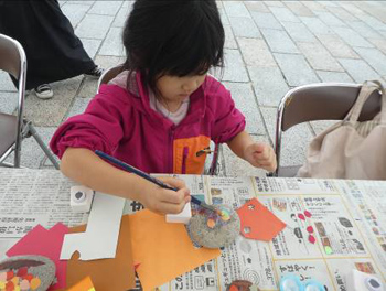 お子さんが石に色紙を貼り付けています。