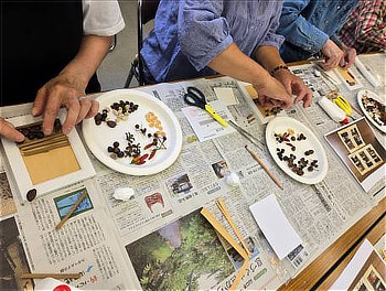 制作に取り組むみなさんの手元(準備した色々な種を、バイキング形式で自由にとってもらい、写真盾に張り付けていきます)