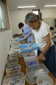 ドライフラワーリース作りの様子。参加者がテーブルに並べられた花材を選んでいる。