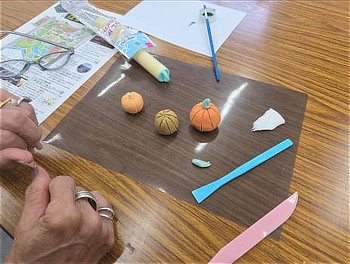 作業シートの上に並べられた出来上がり間近の粘土のカボチャと道具