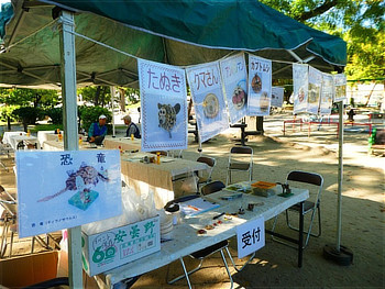 公園内のテントに掲示された『たぬき』『クマさん』『恐竜』などの工作見本掲示物と、『受付』と書かれた工作用の長机
