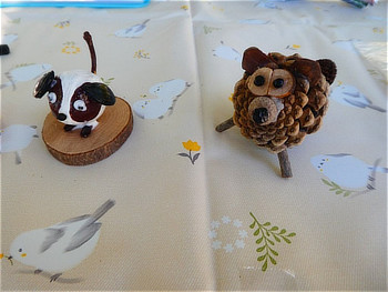 どんぐりや松ぼっくりなどの自然素材で作られた、犬とライオン(またはクマ)の可愛らしい工作作品